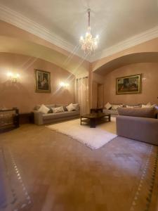 una gran sala de estar con sofás y una lámpara de araña. en Villa les oliviers, en Marrakech