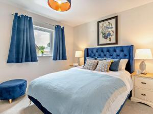 een blauw bed in een slaapkamer met blauwe gordijnen bij 2 Bed in Gower 91724 
