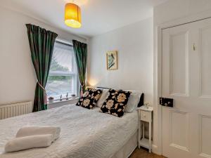 - une chambre dotée d'un lit blanc avec des oreillers noirs et d'une fenêtre dans l'établissement 2 Bed in Wooler 92074, à Wooler