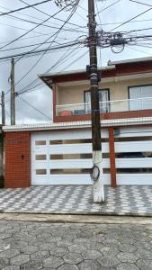 Casa nova condomínio fechado Praia Grande SP في Solemar: عمود أمام منزل وأبواب جراج بيضاء