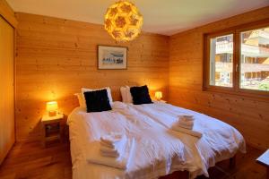 ein Schlafzimmer mit einem großen weißen Bett und einem Kronleuchter in der Unterkunft Duplex Wchimney Overlooking The Village in Champéry