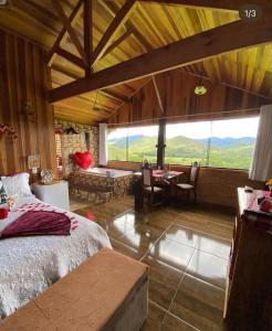 a bedroom with a bed and a table and chairs at Pousada Rancho da Montanha in Visconde De Maua
