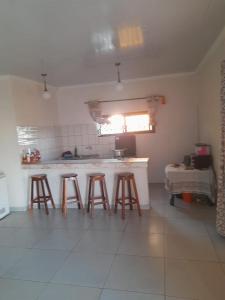 a kitchen with four bar stools in a room at Chidenguele in Chidenguele