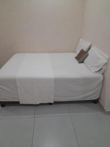 1 cama con sábanas blancas y almohadas en una habitación en Chidenguele en Chidenguele