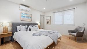 Un dormitorio con una cama y una silla y una ventana. en Ocean Grove Breeze On The Terrace Coastal Apartment, en Ocean Grove