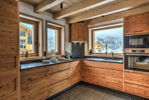 a kitchen with wooden cabinets and a large window at Chalet Belle des Neiges - Alpes Travel - Sleeps 9 in Les Houches