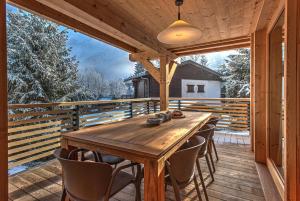 a wooden deck with a wooden table and chairs at Chalet Belle des Neiges - Alpes Travel - Sleeps 9 in Les Houches