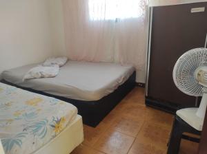 a small bedroom with two beds and a fan at Pousada em Mongaguà Kali 2 in Mongaguá