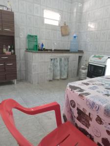 Casa de Férias Arborizada في كانافييراس: كرسي احمر في مطبخ مع طاولة