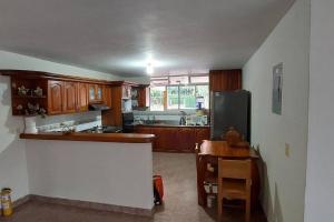 eine Küche mit Holzschränken, einem Tisch und einem Kühlschrank in der Unterkunft Finca en Copacabana con piscina y cancha de futbol in Girardota