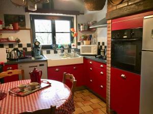 een keuken met rode kasten en een tafel met een rode tafelkleed bij Gîte Vadelaincourt, 4 pièces, 4 personnes - FR-1-585-67 in Vadelaincourt