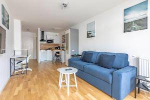 ein Wohnzimmer mit einem blauen Sofa und einem Tisch in der Unterkunft Studio Neuf proche Parc de Sceaux / RER in Sceaux
