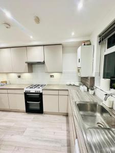 a kitchen with white cabinets and a stove and a sink at Studio 12 in London