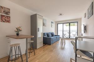 ein Wohnzimmer mit einem blauen Sofa und einem Tisch in der Unterkunft Studio Neuf proche Parc de Sceaux / RER in Sceaux