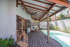 a wooden deck next to a swimming pool with a pergola at Belukar Villas in Gili Trawangan