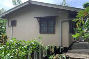 un pequeño edificio blanco con ventana y porche en Canopy cottage, en Honiara