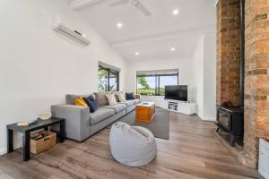 a living room with a couch and a tv at Willunga House - Fireplace Vineyard Views in Willunga