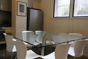 a glass dining room table with white chairs at The Walkup Southbank in Melbourne