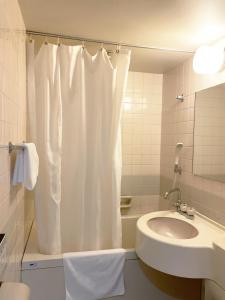 a bathroom with a white shower curtain and a sink at Hotel Royal Oak Gotanda in Tokyo