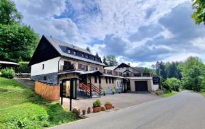 een groot wit huis met een zwart dak bij Bylo Nebylo apartmány in Vítkovice