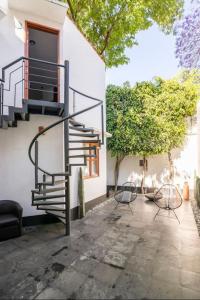un patio con 2 sillas y una escalera junto a un edificio en Siete Puertas Coyoacán en Ciudad de México