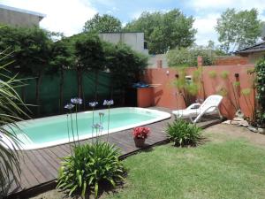 a swimming pool in a garden with a chair and flowers at Casa en Santa Teresita in Santa Teresita