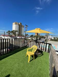 a yellow chair and an umbrella on a balcony at Beach Bungalow in Rosarito