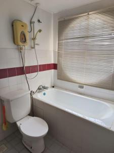 een badkamer met een toilet en een bad met een raam bij KZ Homestay PD in Port Dickson