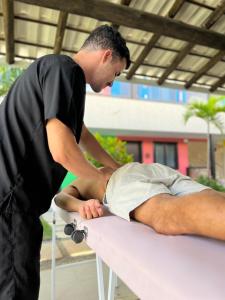 un hombre está cortando a un hombre de nuevo en una mesa en Pousada Toca do Ceará en Regência