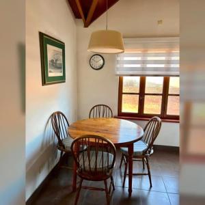 a dining room table with chairs and a clock on the wall at Colibrí Tempo in Esquel