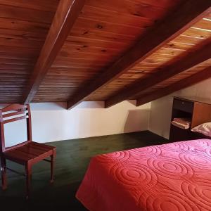 a bedroom with a red bed and a wooden ceiling at Las Calandrias in Funes