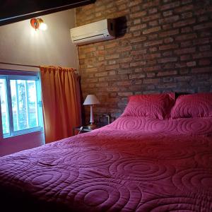 a red bed in a room with a brick wall at Las Calandrias in Funes