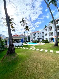 a lawn with palm trees and buildings in the background at Beach and pool life in Punta Cana