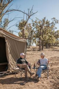 Due uomini seduti su sedie di fronte a una tenda di Gilgooma 