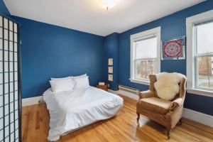 Spacious & Cozy Home in Highfield St Moncton في مونكتون: غرفة نوم زرقاء مع سرير وكرسي