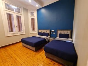 2 Betten in einem Zimmer mit blauen Wänden und Fenstern in der Unterkunft Cairo Hub in Kairo