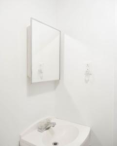 a white bathroom with a sink and a mirror at Cozy studio apartment - 240 in Montréal