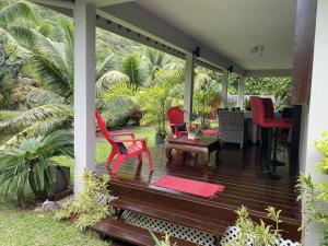 a porch with red chairs and a table at MOOREA - Villa Tiahura in Hauru