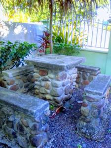 una pared de piedra y dos bancos de piedra en un jardín en come and enjoy singing birds, en Calibishie