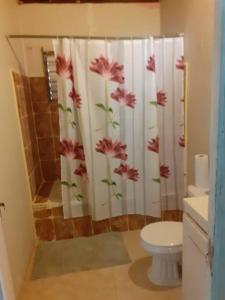 a bathroom with a shower curtain with flowers on it at D'RESORT WAKE UP AND LIVE YAH in Spanish Town