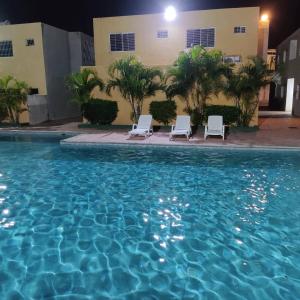Tucacas的住宿－Apartamento Playa Ciudad Flamingo Tucacas Chichiriviche，一座带两把躺椅的游泳池以及一座建筑