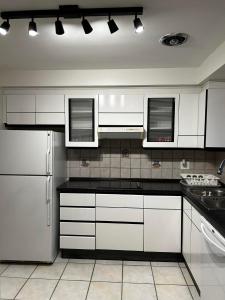 uma cozinha com armários brancos e um frigorífico branco em Premium home with Garden view, private parking em Toronto