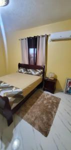 a bedroom with a bed and a window and a rug at Finest Accommodation #528 Stem Ave Jacaranda 1 bedroom in Spanish Town