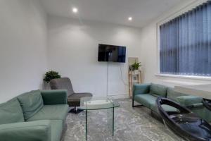 a living room with two green couches and a tv at Tarleton house in Stoke on Trent