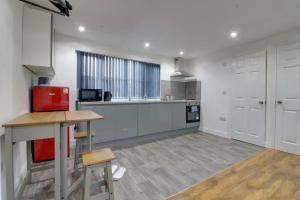 a large kitchen with white cabinets and a red appliance at Tarleton house in Stoke on Trent