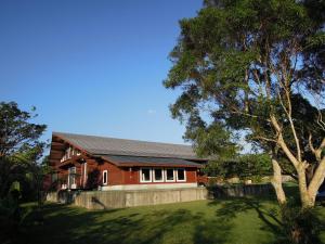 una casa rossa con un albero di fronte di Pension Prussian Blue a Miyakojima