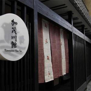 una señal en el lateral de un edificio con toallas rojas y blancas en Kamogawakan en Kyoto