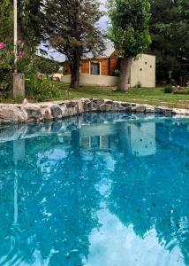 una grande piscina di acqua blu di fronte a una casa di Fiordo B&B and Beer-Spa a Potrerillos