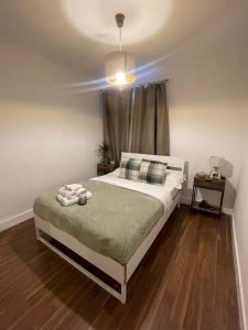 a bedroom with a bed with a green blanket at Park View Homestay in Barking