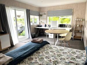 a bedroom with a bed and a kitchen with a table at Kotahi Cottage in Cambridge
